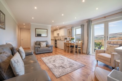 The living space is spacious and bright with garden and hill views