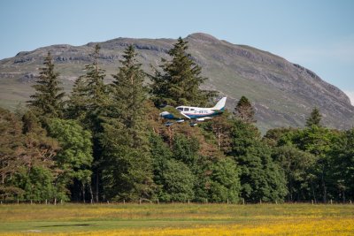 Light aircraft landing on the airfield in front of the house