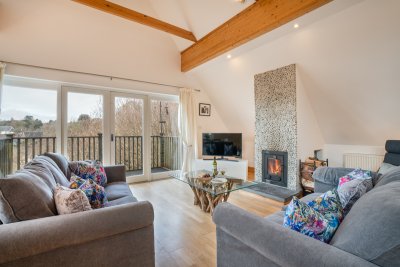 The living area is a wonderful space with lofty ceilings, wood burning stove and characterful beams