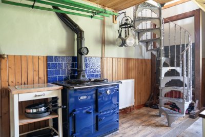 Range cooker in the School House with spiral staircase leading to second bedroom