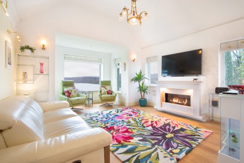 Light and airy living room complete with luxury furnishings, fireplace and sea view