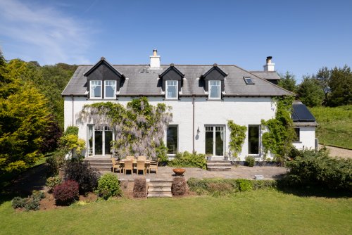 Torrbreac, with stunning mature gardens, a wisteria vine climbing across the cottage and a sun-kissed, sea view patio